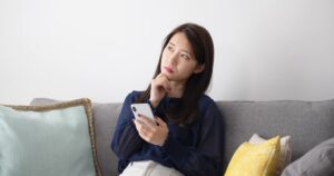 スマホを持って考えている女性
