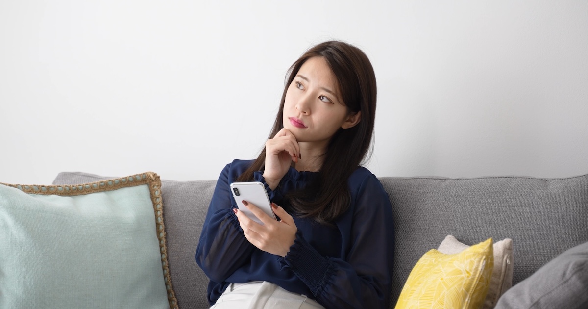 スマホを持って考えている女性